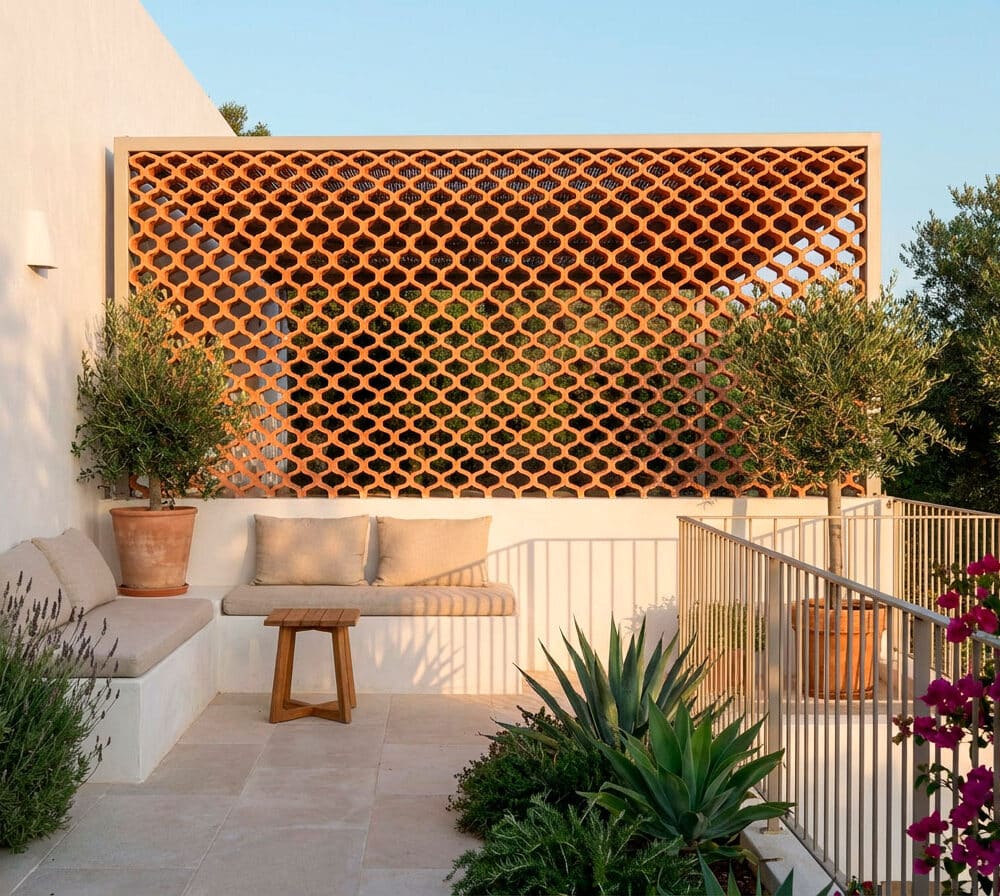 Celosía árabe de cerámica decorativa en una terraza soleada con banco y plantas.