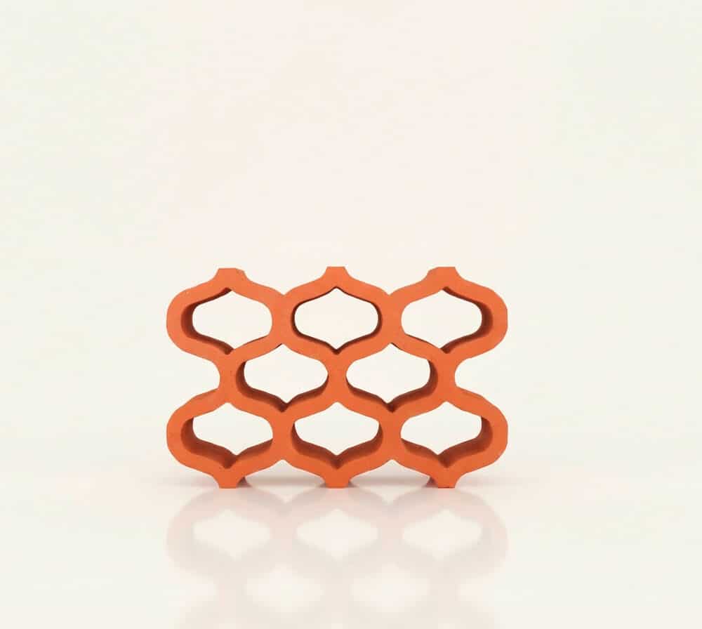 Celosía arabe de cerámica roja con patrón decorativo sobre fondo blanco.