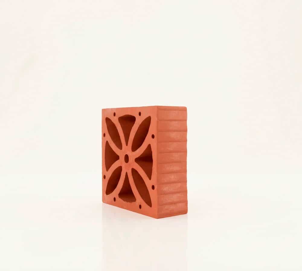 Una celosía flor de terracota con patrón decorativo sobre fondo neutro.