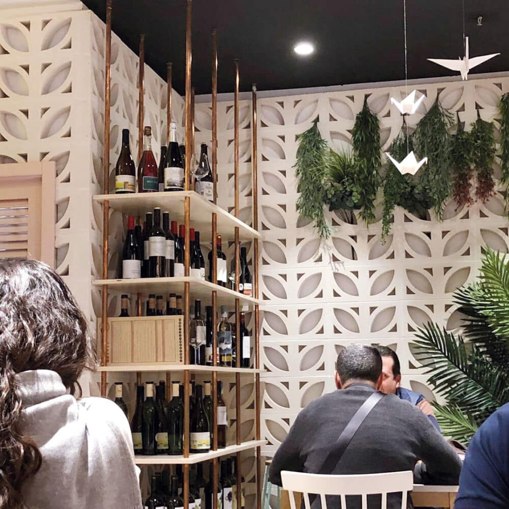 Pared decorativa de celosía Ficus blanca en un restaurante con estantes de vino.