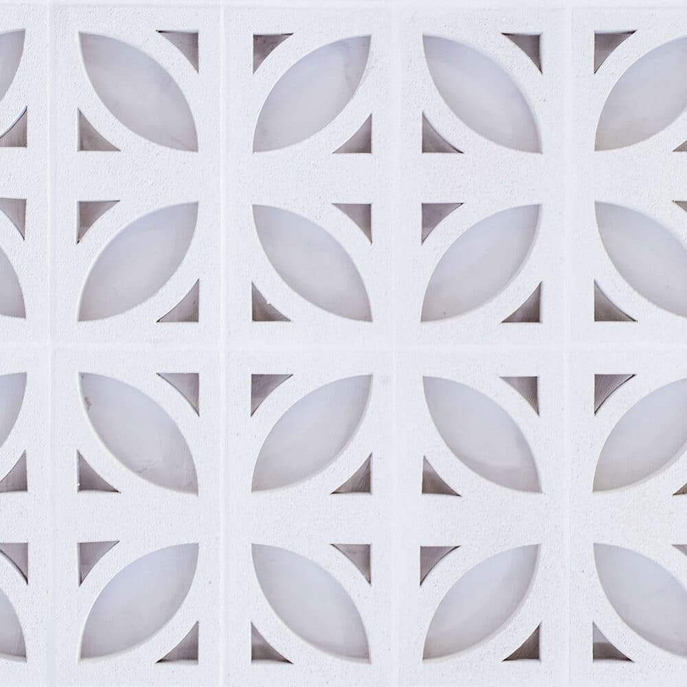 Celosía Ficus blanca con patrón de hojas y triángulos. La superficie es texturizada.