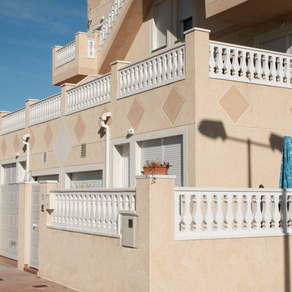 Terraza de vivienda moderna con balaustres blancos decorativos en la fachada