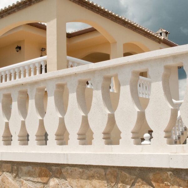 Balaustrada moderna de color blanco con formas estilizadas, rodeada de un ambiente residencial.