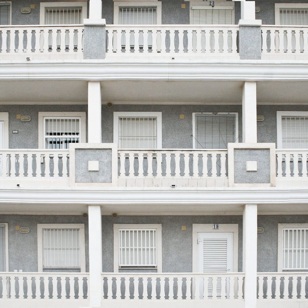 Fachada de edificio de varios pisos con barandillas de balaustres en los balcones.