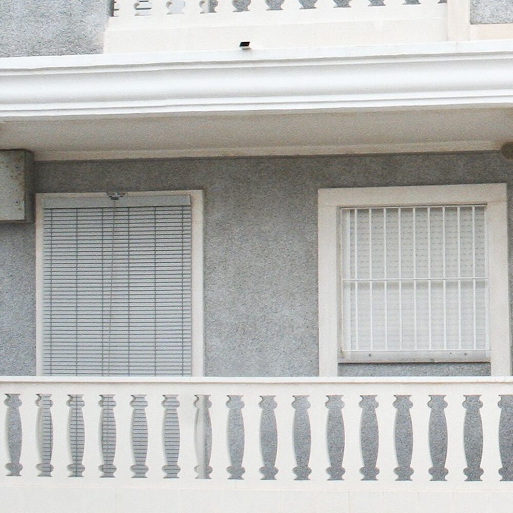 Primer plano de una barandilla con balaustres decorativos en el balcón de un edificio.