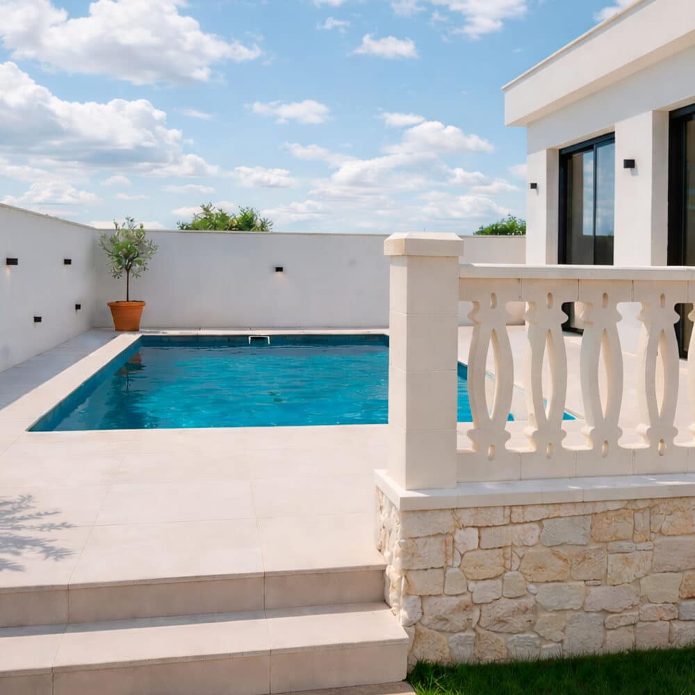 Una balaustrada exterior de piedra con diseño de corazones decora una terraza con piscina.