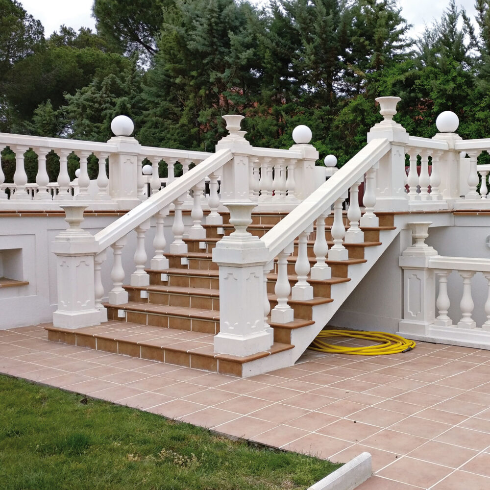 Escalinata de estilo clásico con balaustrada blanca en un jardín