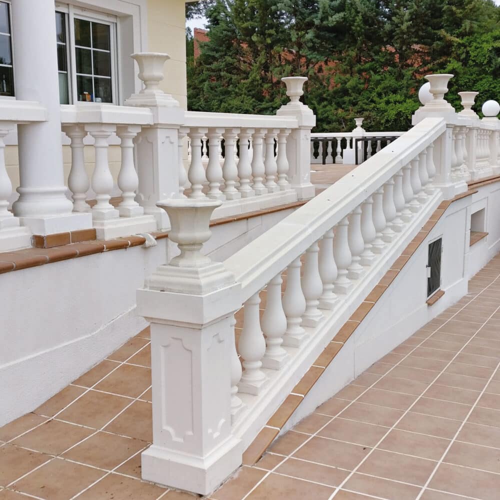 Balaustrada blanca decorativa en una escalera exterior con detalles de columnas