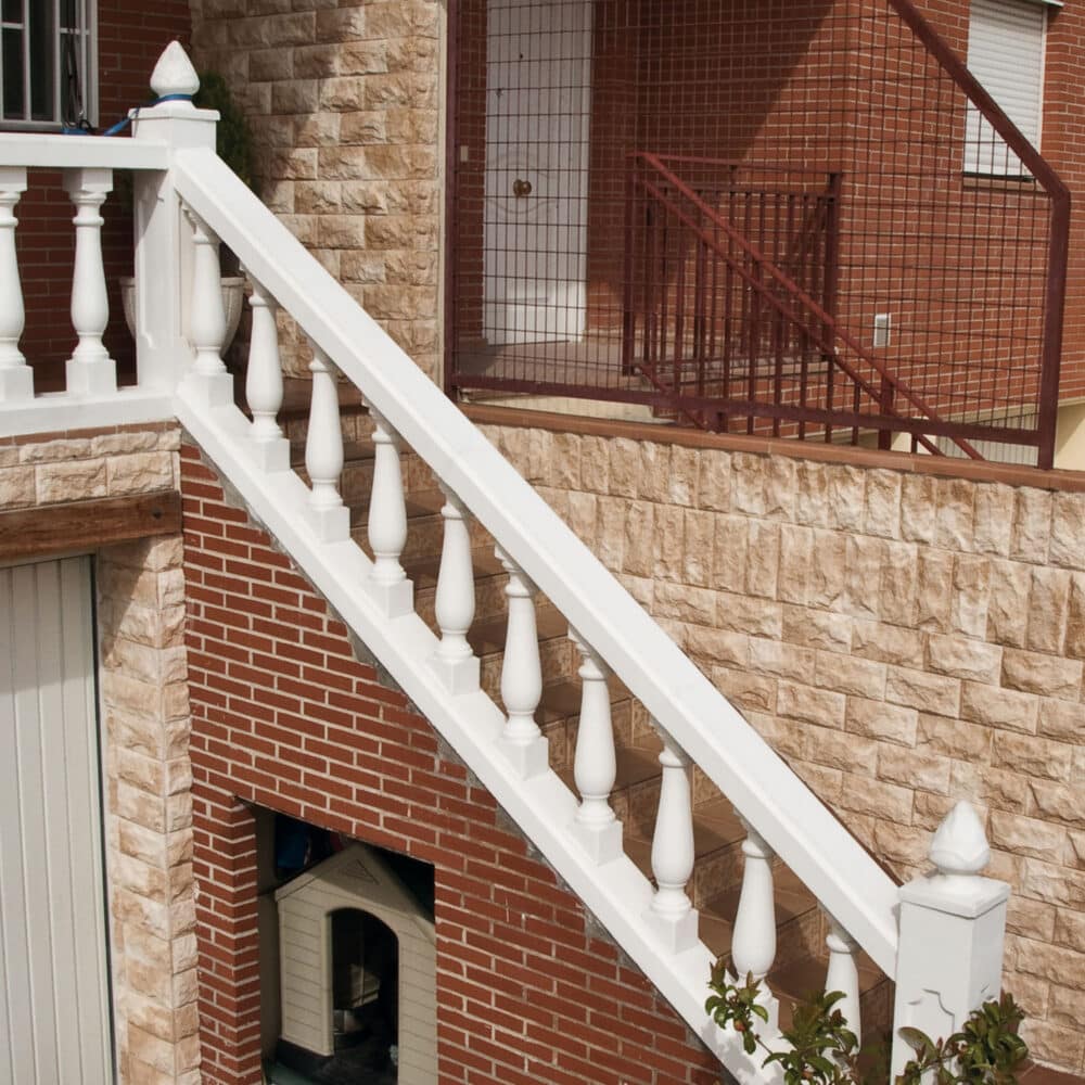 Escalera exterior con balaustrada blanca en casa de ladrillo rojo