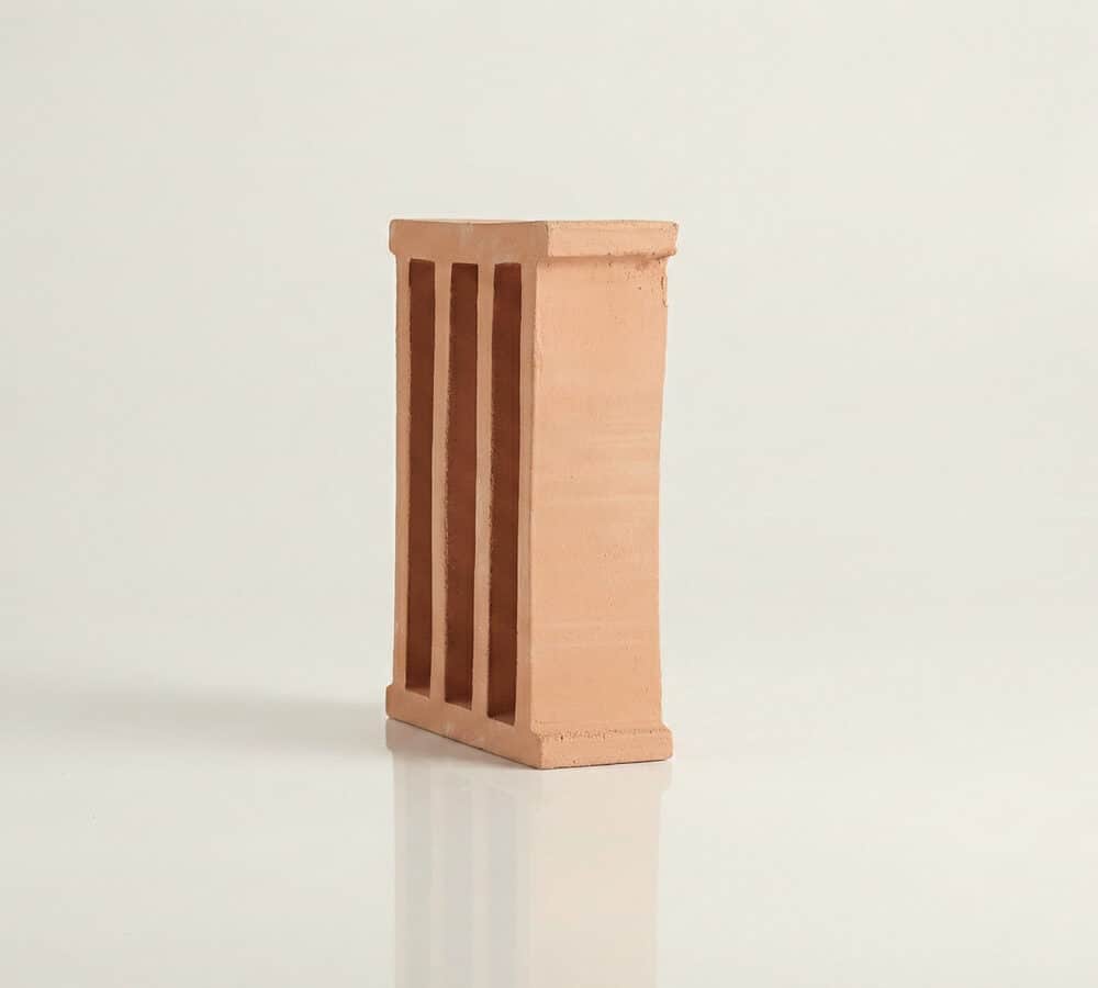 Una celosía de cerámica roja con tres aberturas verticales sobre fondo blanco. Ideal para terraza.